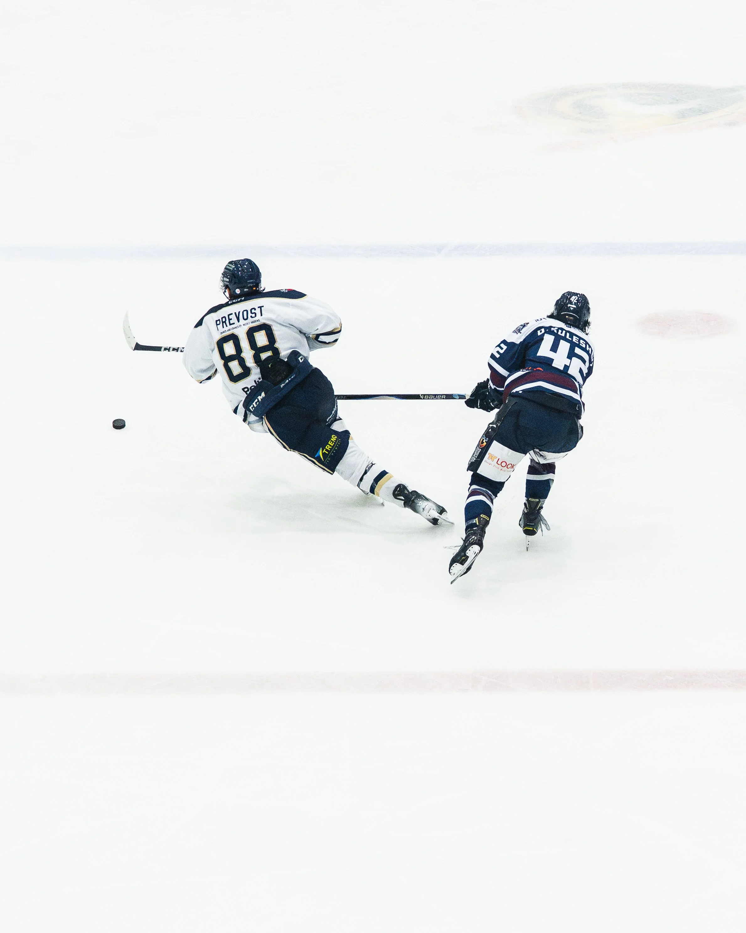 Two ice hockey players in action on the ice rink, competing for the puck.