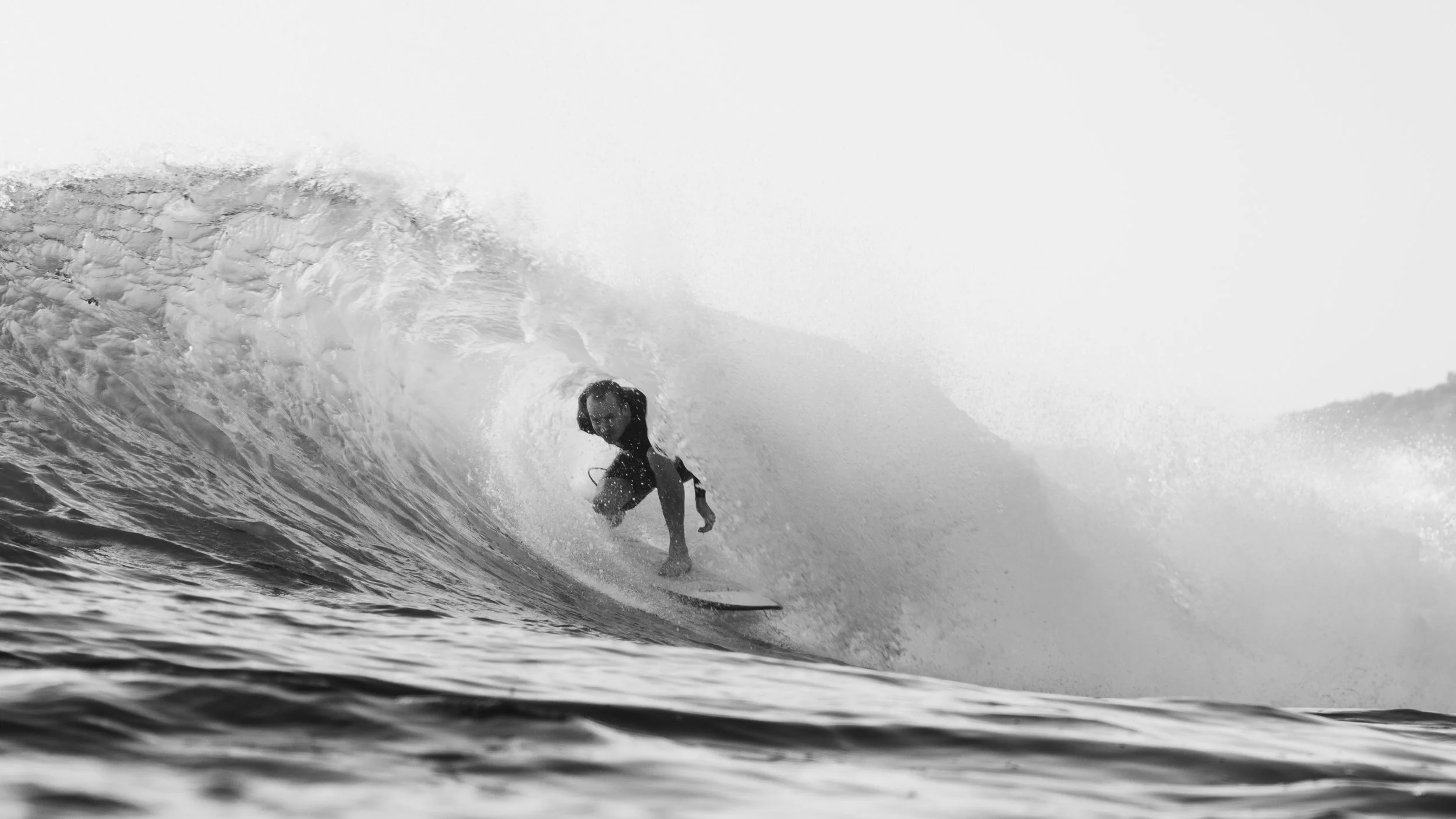 A person surfing on a wave in the ocean, black and white photo.