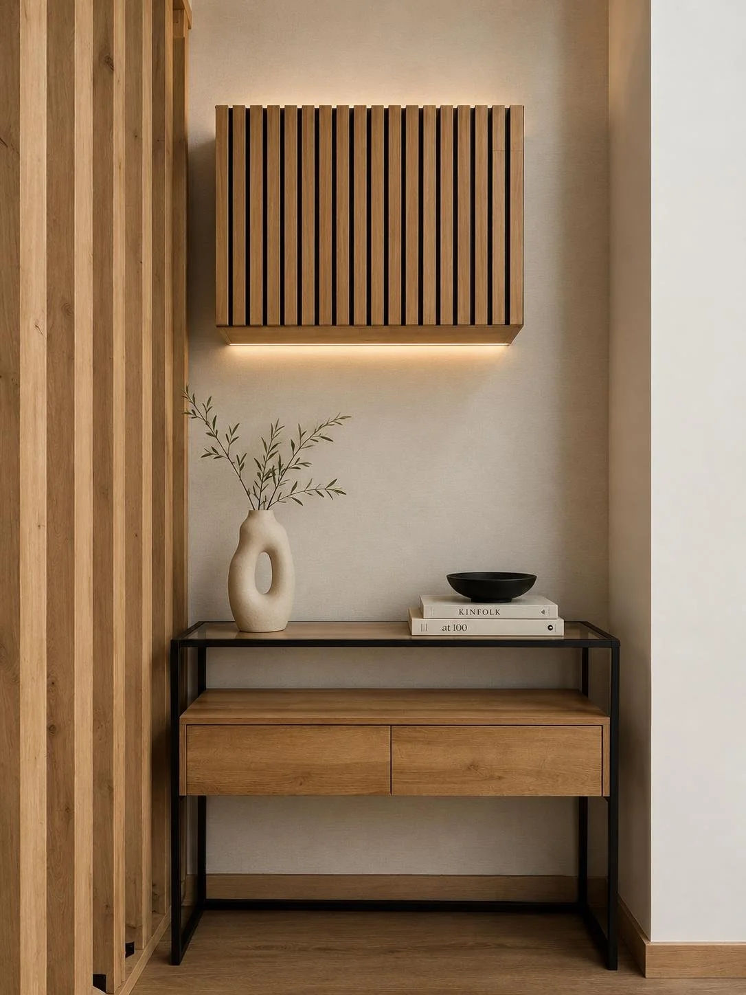 Decoração minimalista com mesa de madeira e estrutura metálica, vaso com galhos secos, livros, tigela preta e painel de madeira na parede.