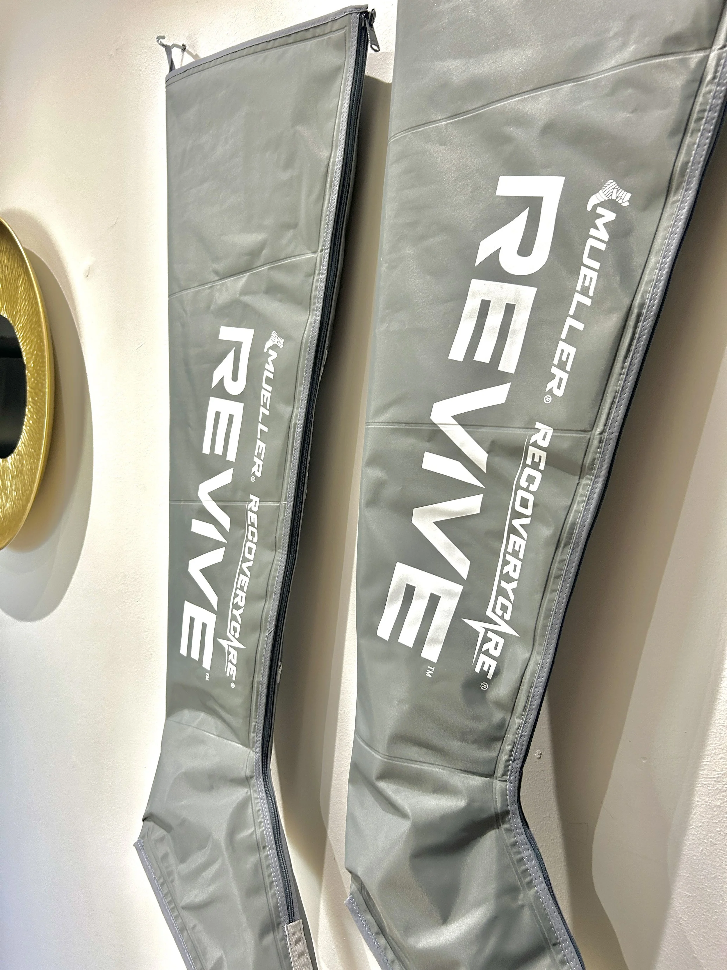 Two gray MaxxRecoveRx recovery bags with zippers, lying flat on a white surface, with the brand name printed on the side.