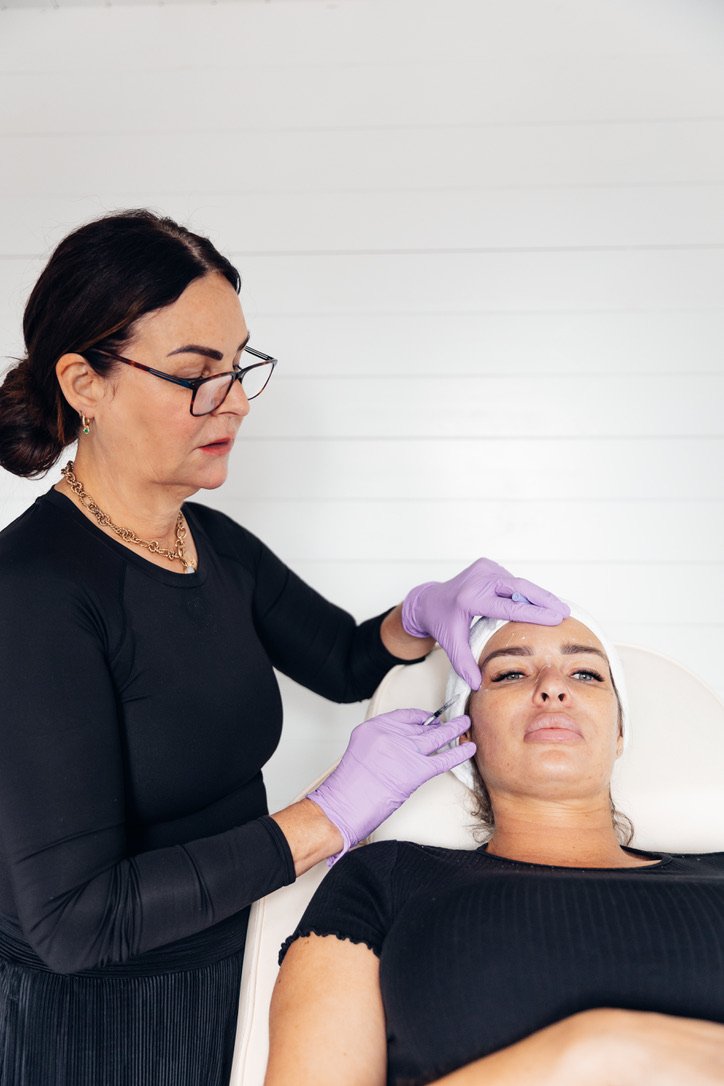 A nurse practitioner performing dermal filler treatment on a female patient to improve facial volume and definition at a modern skin clinic in Broadstone dorset