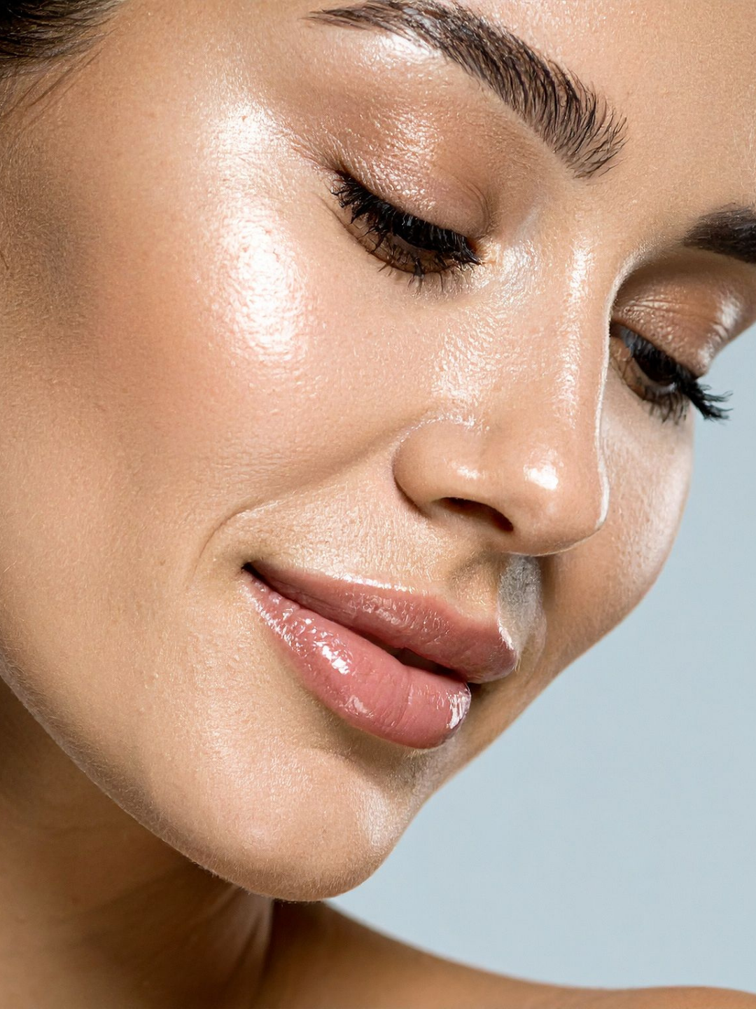 Side image of a woman with beautiful dewy skin looking down in content following Profhilo filler treatment to achieve glowing skin in Bournemouth
