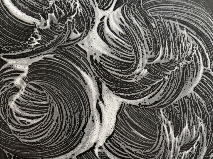 Black and white abstract swirl pattern with foam and soap lines.