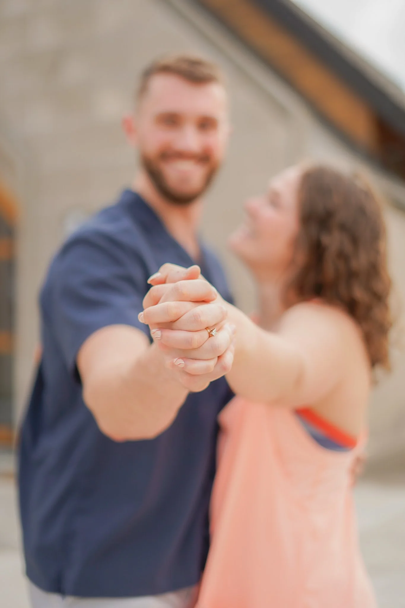 A blurry photo of a man and woman dancing, holding hands, smiling, in an indoor setting.