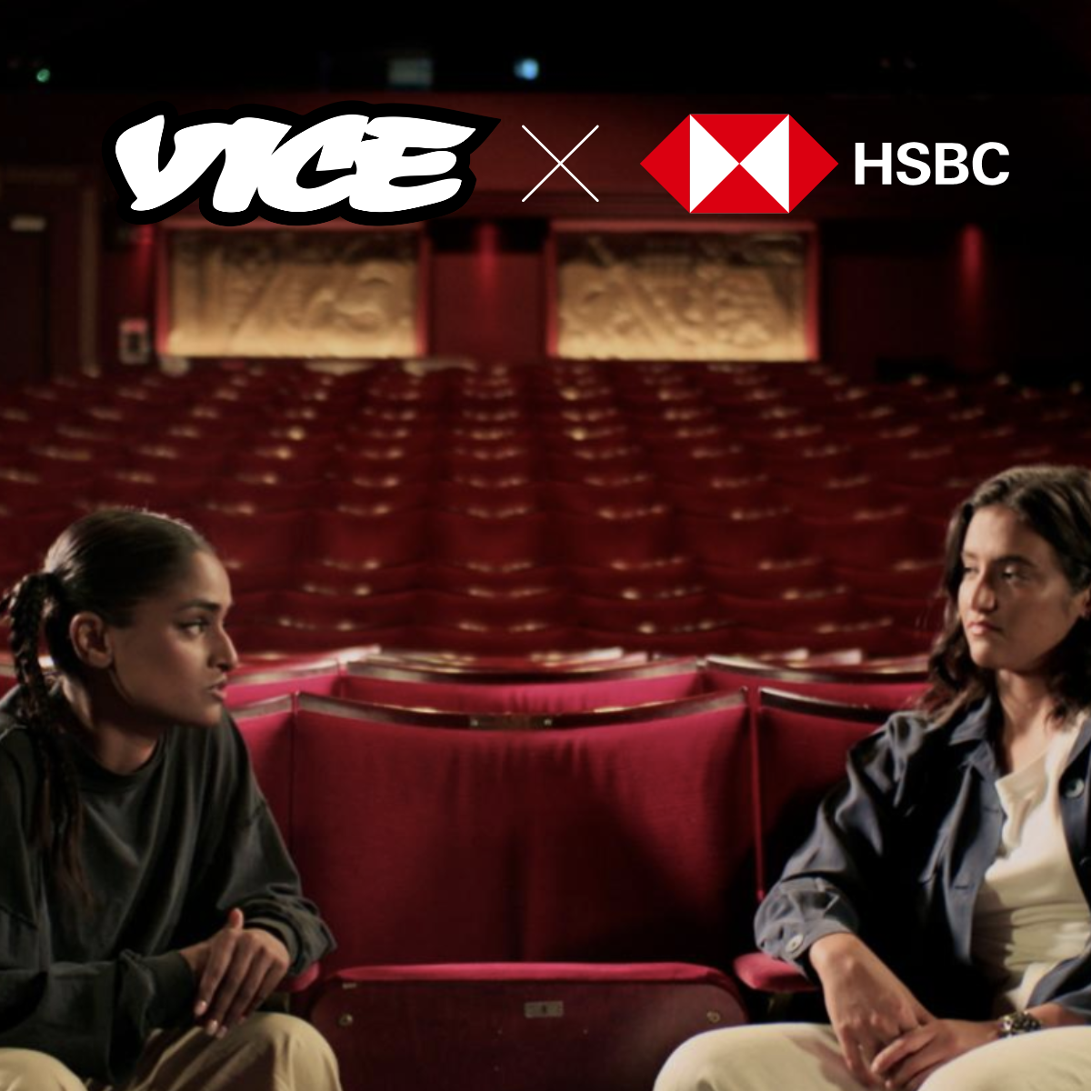 The image shows an empty red theater auditorium with two women seated in the foreground facing each other, and logos of VICE and HSBC above, with a dark background.