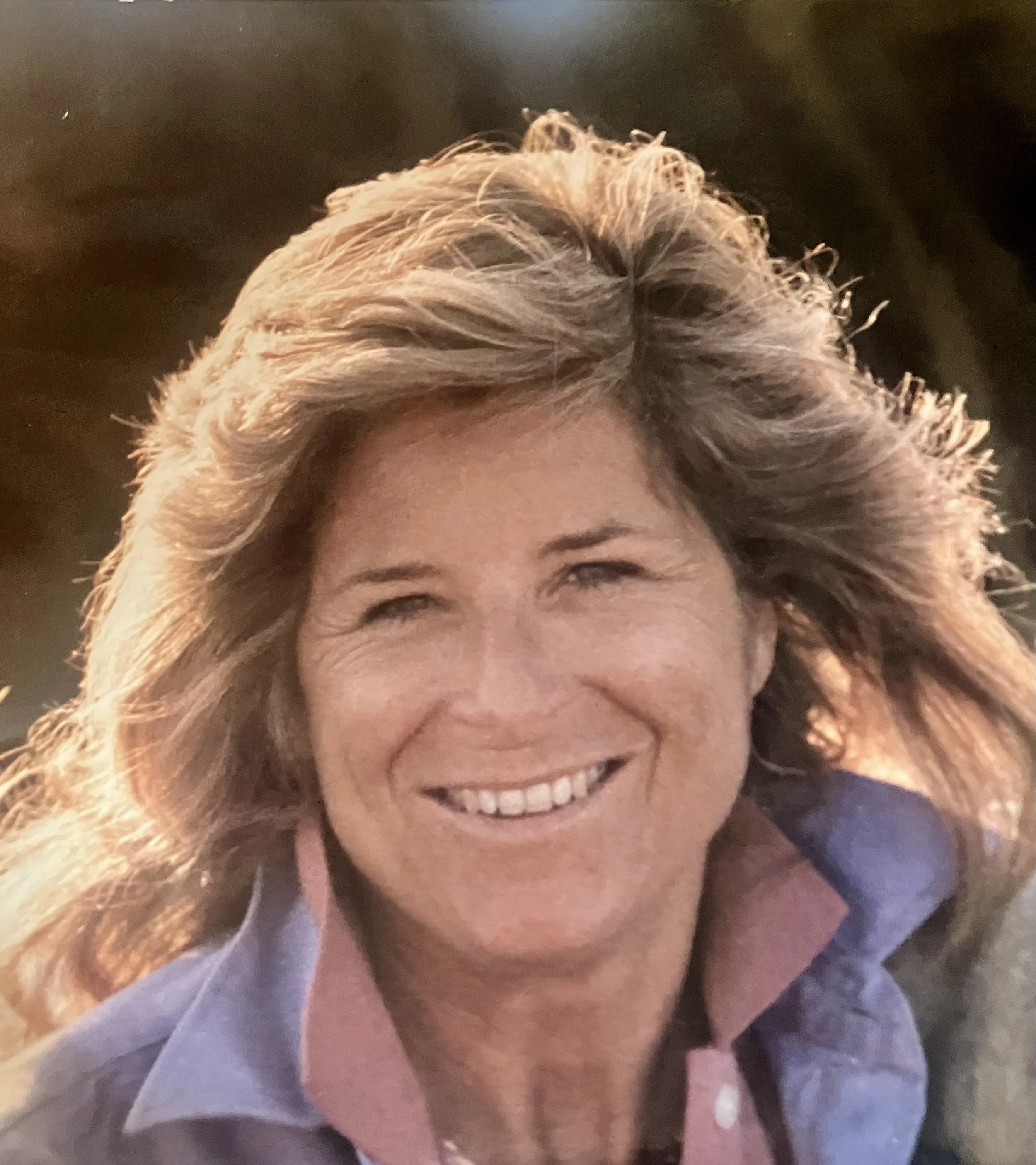 Smiling woman with curly blonde hair wearing a navy top.