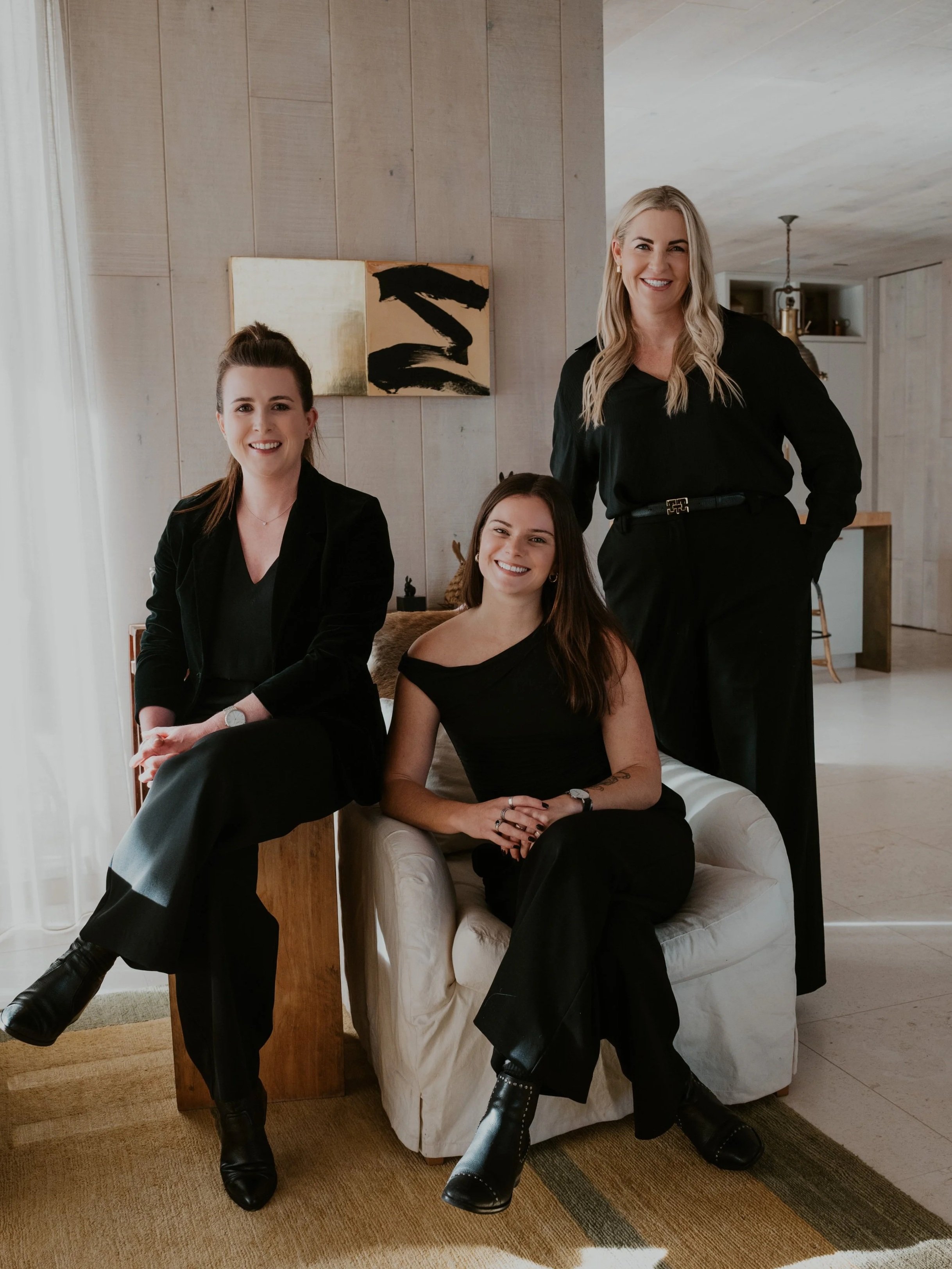 The Elite Management team dressed in black, sitting together in a living room