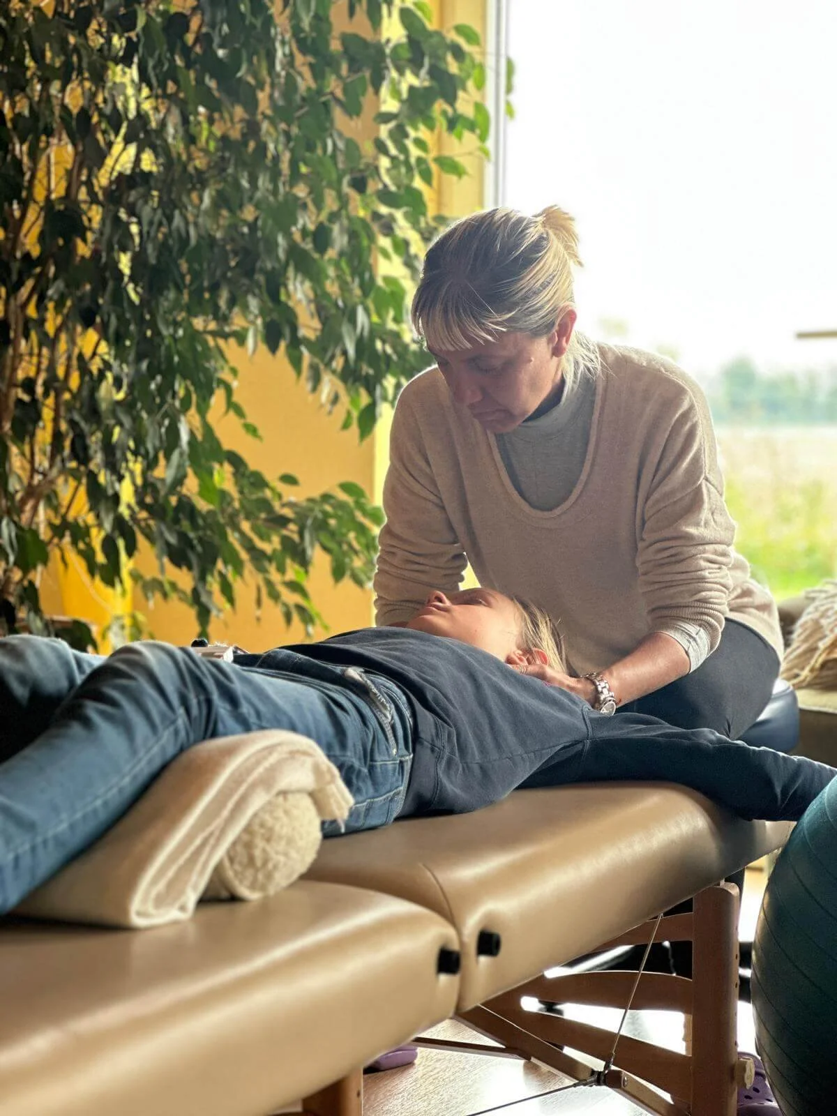 Vanessa Keel performing a gentle neuromotor treatment on a child's head and neck while the child is lying on their back in Zurich to relieve tension and headaches.
