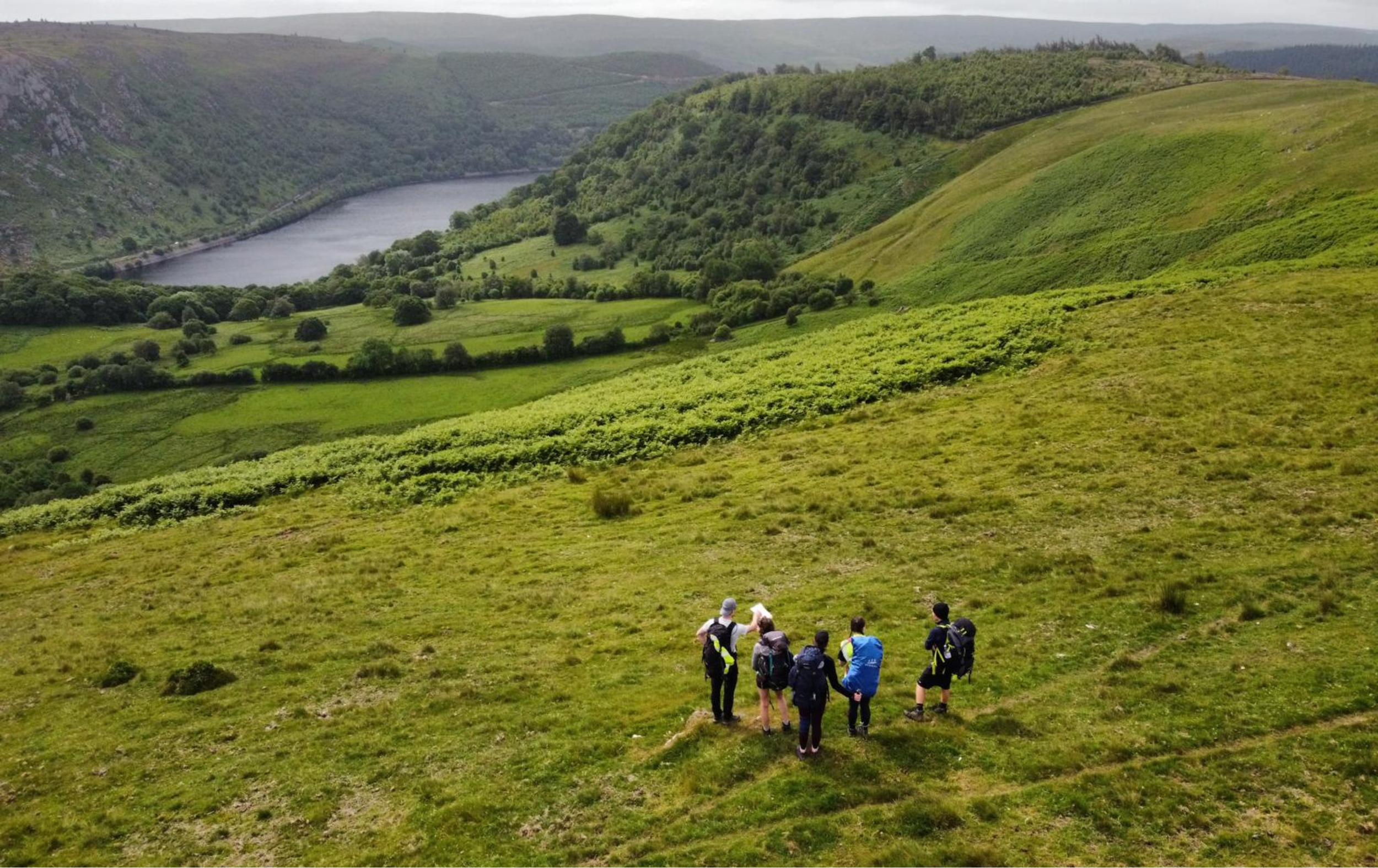 A group of six hikers with backpacks on a wilderness expedition in the elan valley, mid Wales.