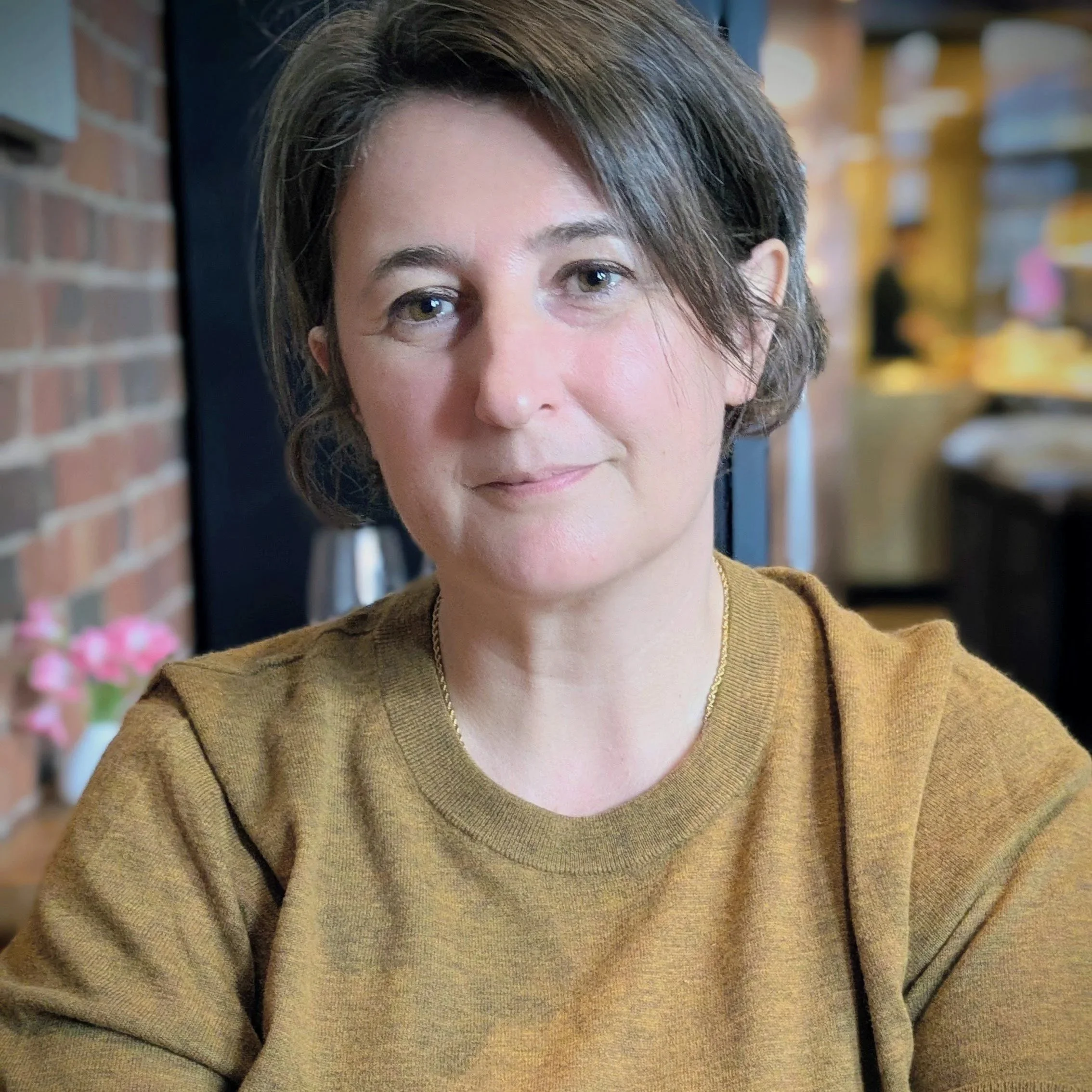 Photo of Carina Badger in a yellow top and short brown hair looking at camera