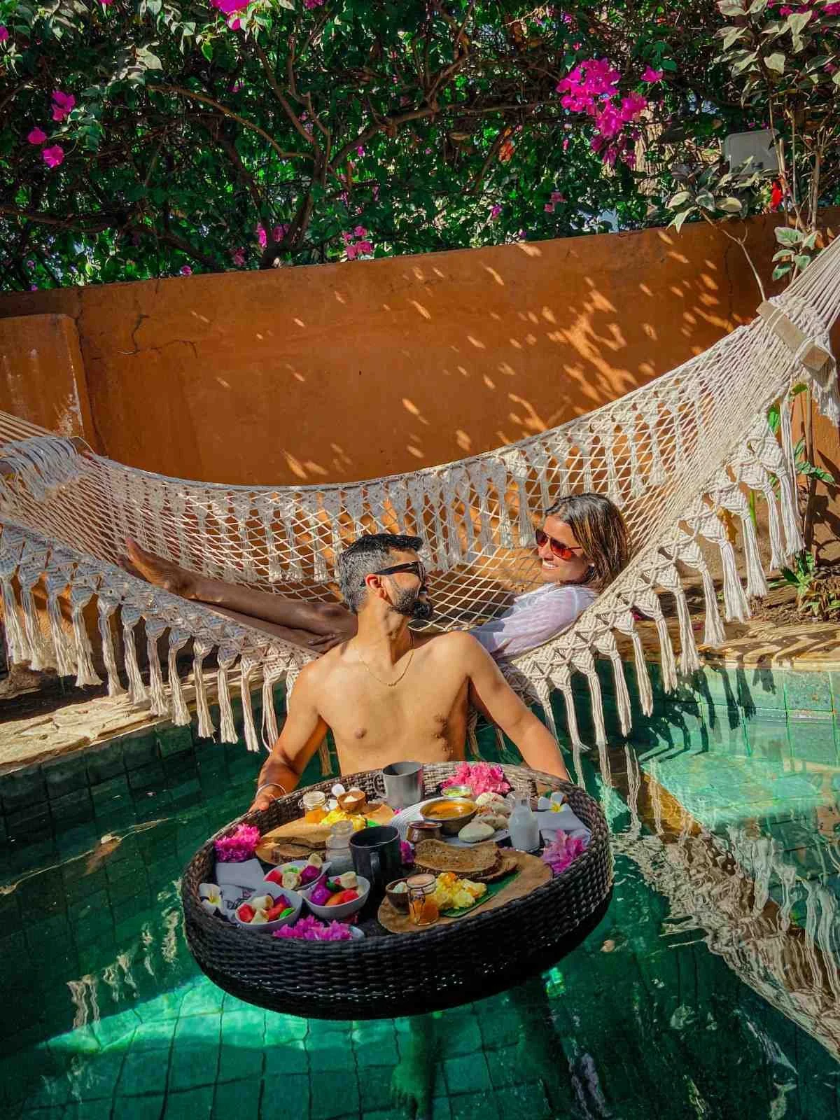 Couple enjoying a floating breakfast and relaxing in a hammock by the pool at Pesona Beach Resort