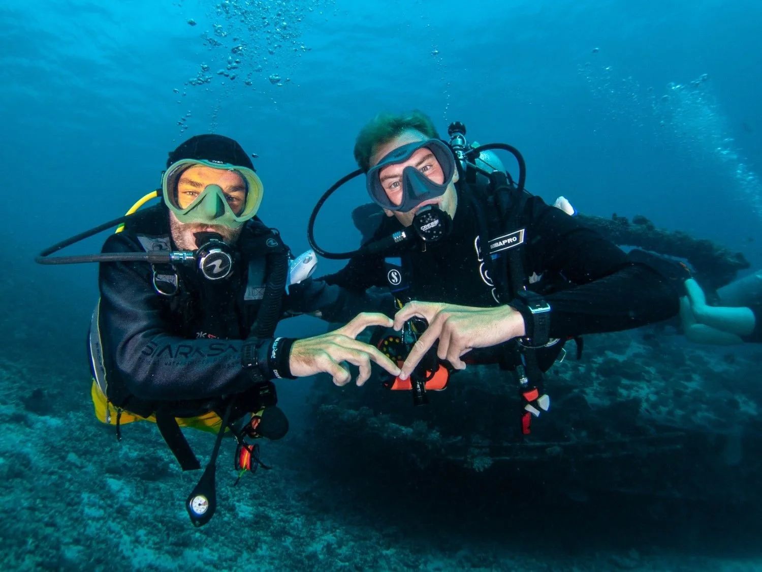 Two scuba divers from Dive Central Gili posing underwater near a coral reef in Gili Trawangan.