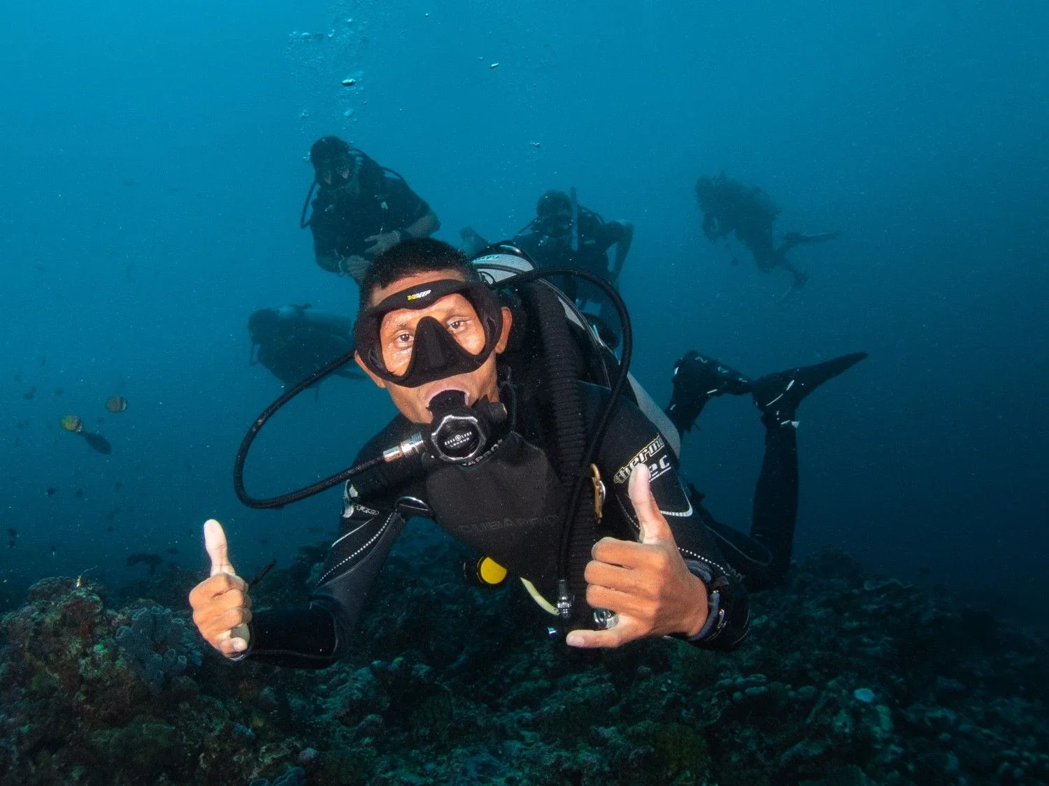 Certified scuba divers exploring coral reefs in the clear waters of Gili Trawangan