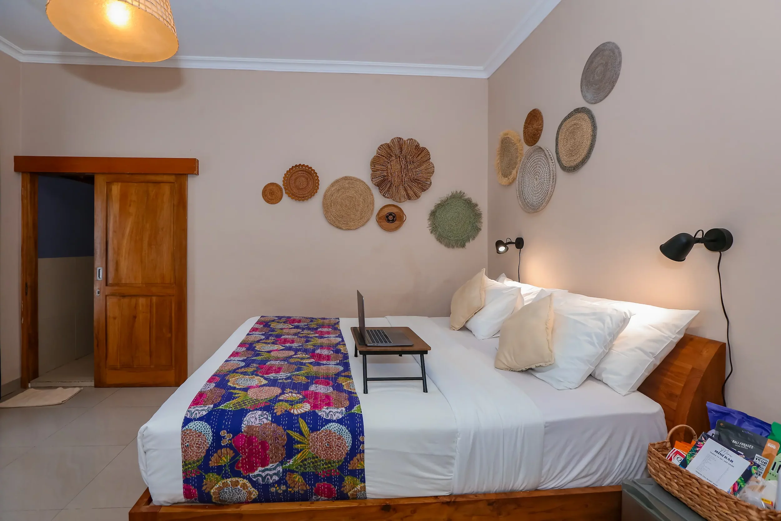 First-floor room with a king bed, colourful floral runner and woven wall decorations at Pesona Beach Resort