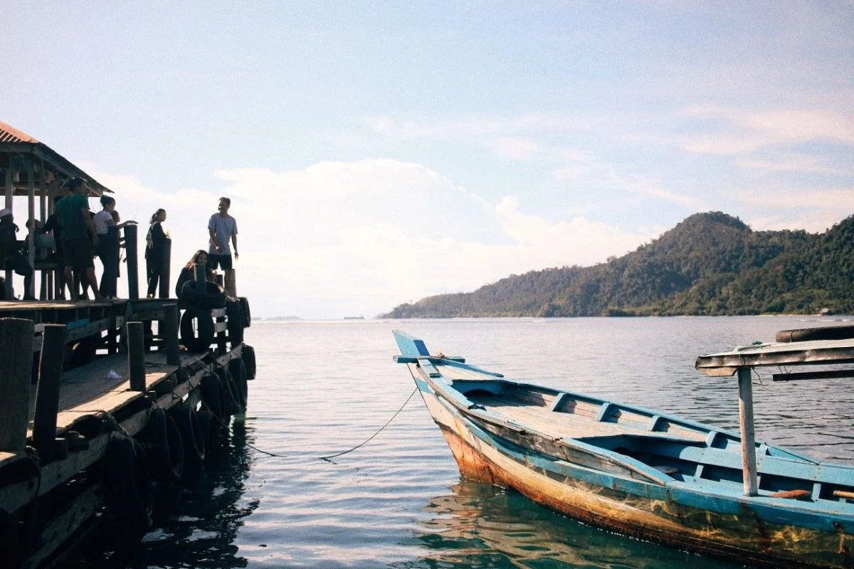 Public boat at Gili Trawangan harbour with a wooden jetty, calm sea, and surrounding tropical islands