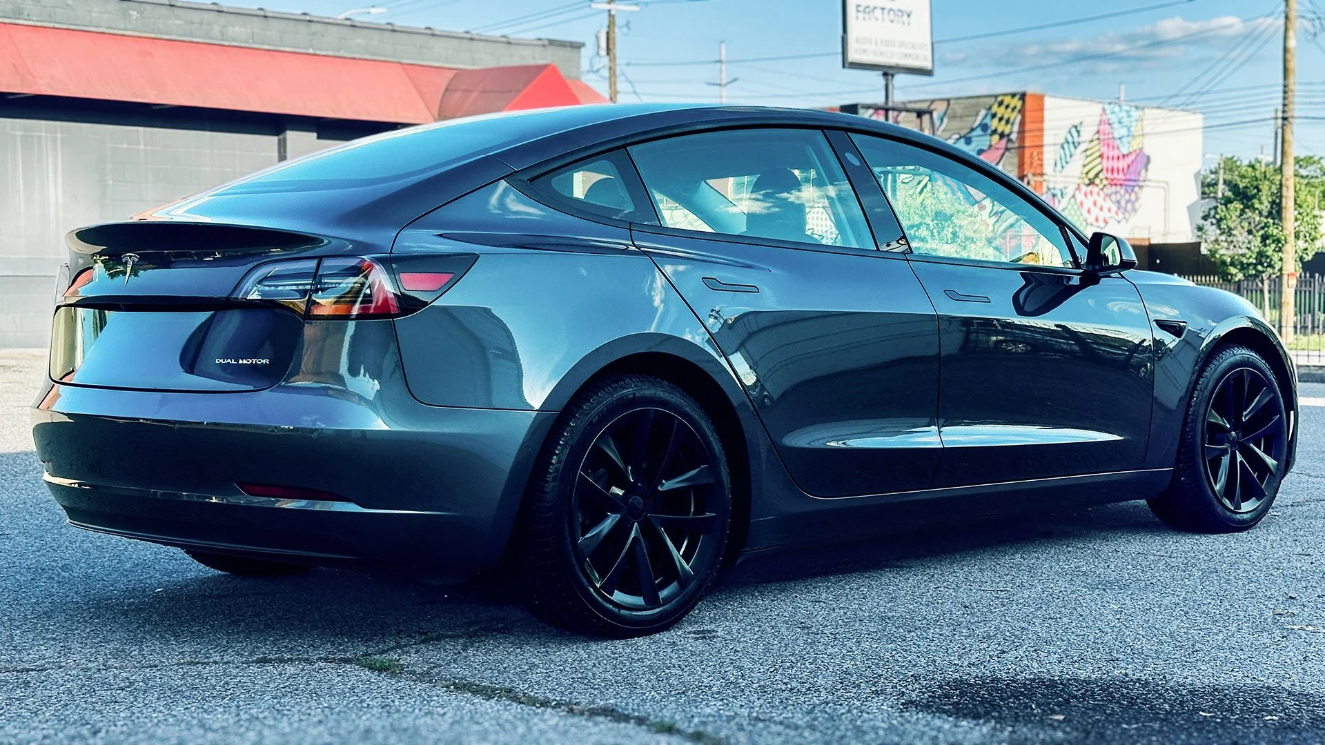 A sleek, dark gray Tesla Model 3 electric car parked outdoors Luxdream Car Detailing, Louisville Ky