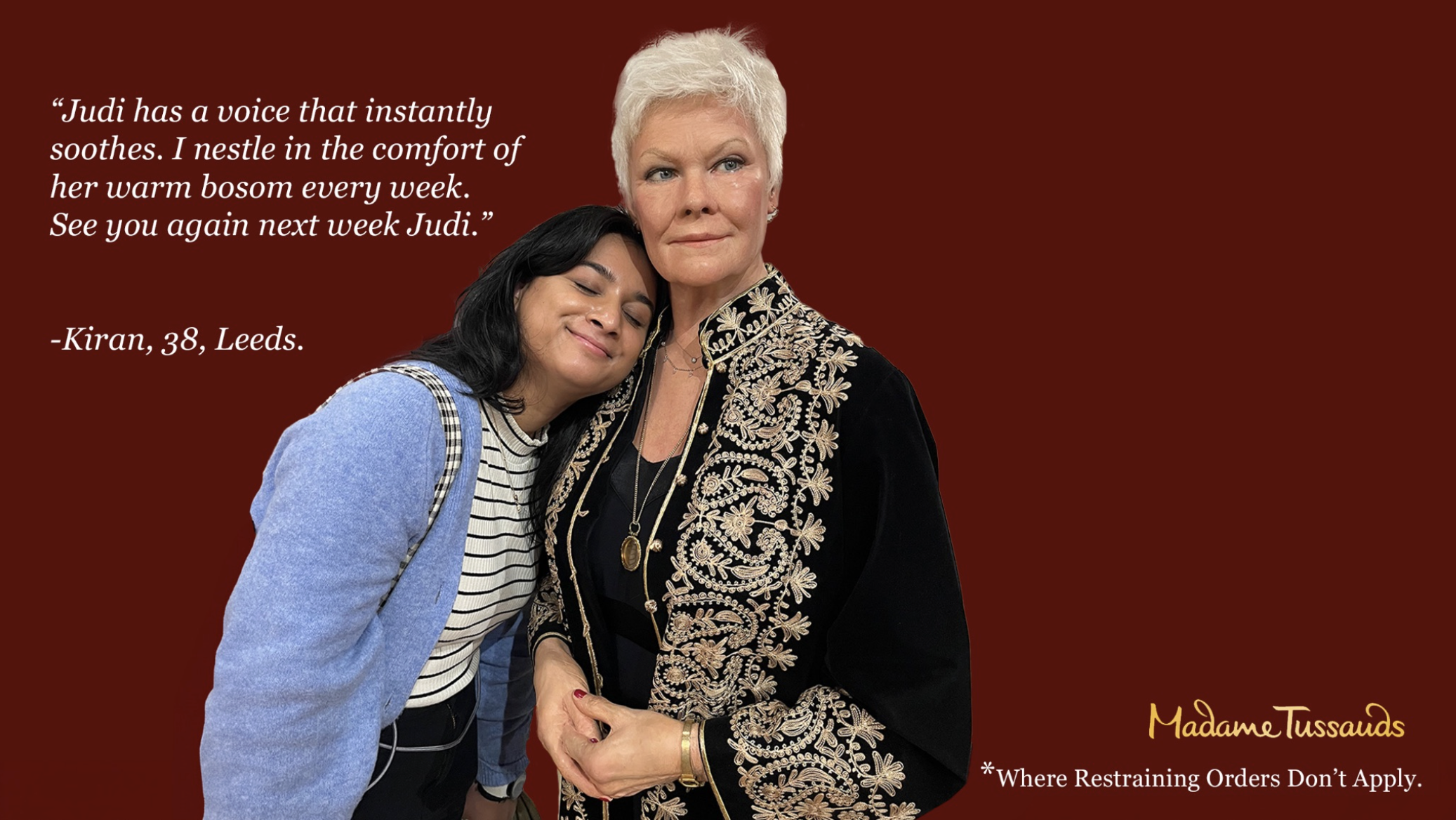 A woman with white hair and a black and gold embroidered jacket holds hands with a woman with long black hair, a striped shirt, and a blue cardigan. They are standing in front of a dark red background with quote text about Judi and a Madamme Tussauds logo.