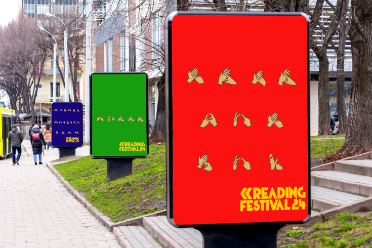 Street scene with digital signboards promoting a reading festival, surrounded by leafless trees and people walking on the sidewalk.