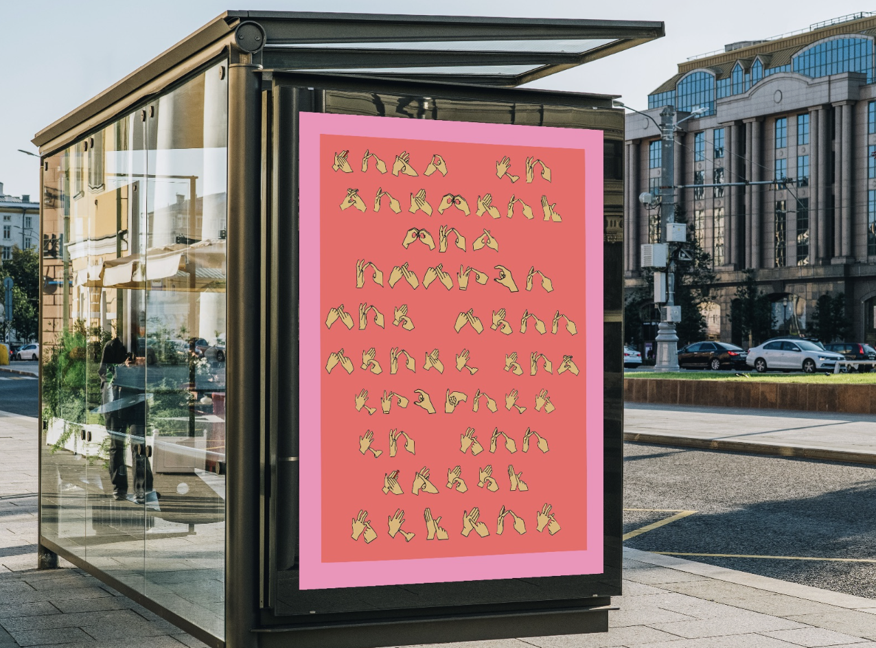 A digital billboard displaying the alphabet in American Sign Language hand signs on a pink background in an urban setting.