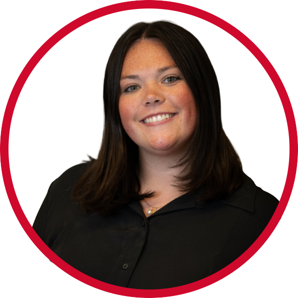A young woman with shoulder-length dark brown hair, smiling, wearing a black shirt, against a white background with a red circular border.
