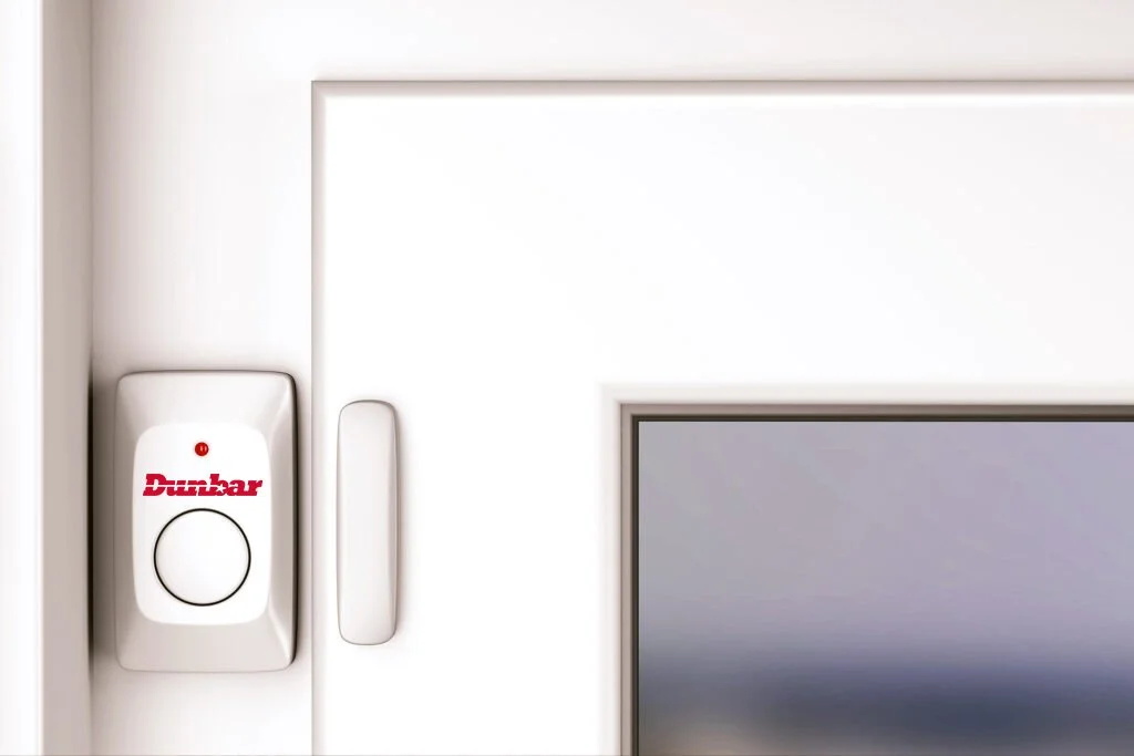 Close-up of a white door with a Dutton alarm keypad and a door handle.