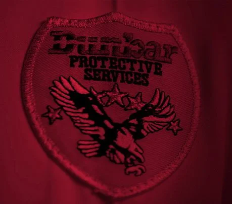 Close-up of a red tactical patch with a black eagle, stars, and the text 'Bulletproof Protective Services'.