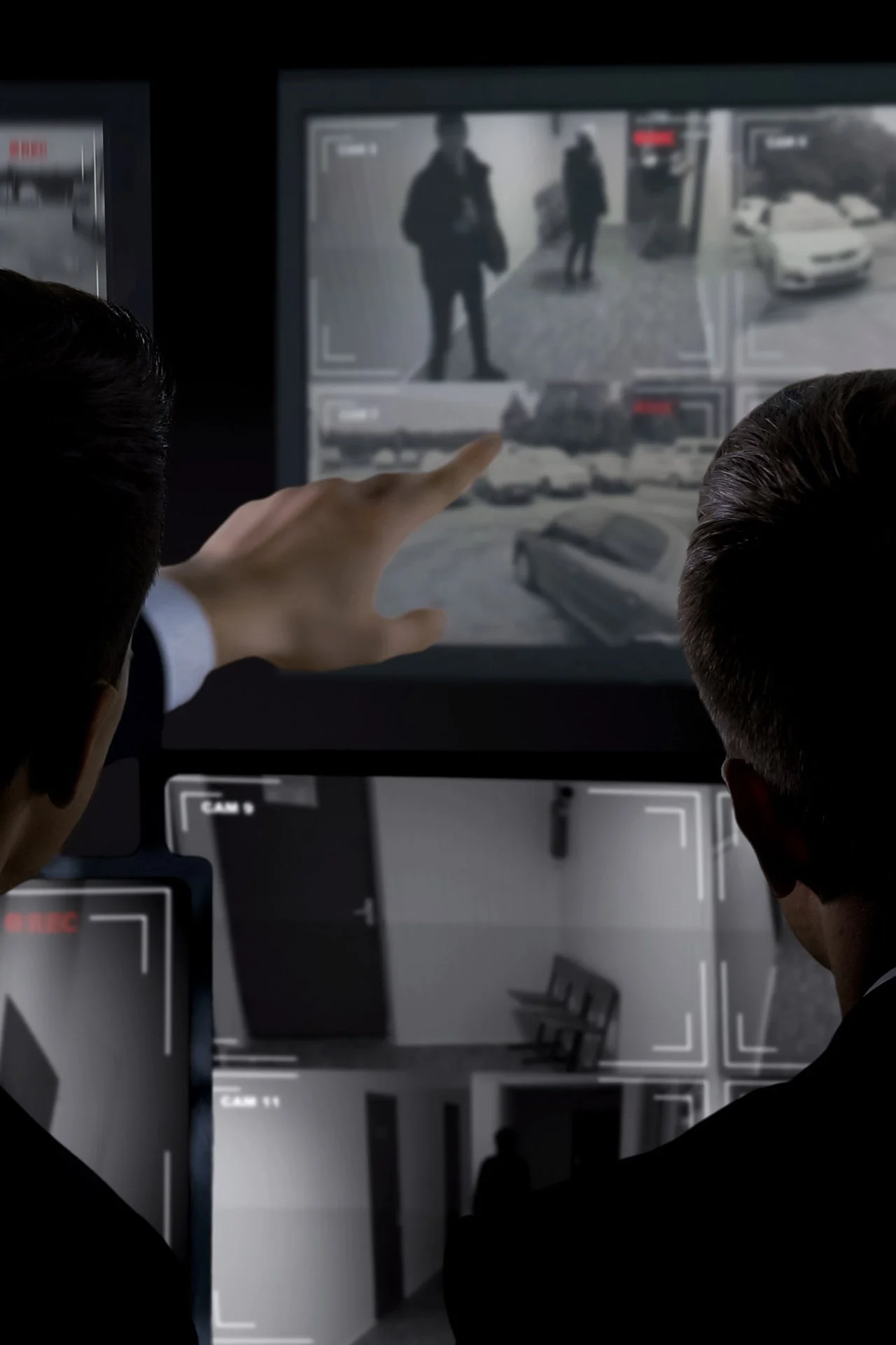 Security camera footage displayed on a monitor showing two individuals in a public place, possibly a shopping mall or transit station.