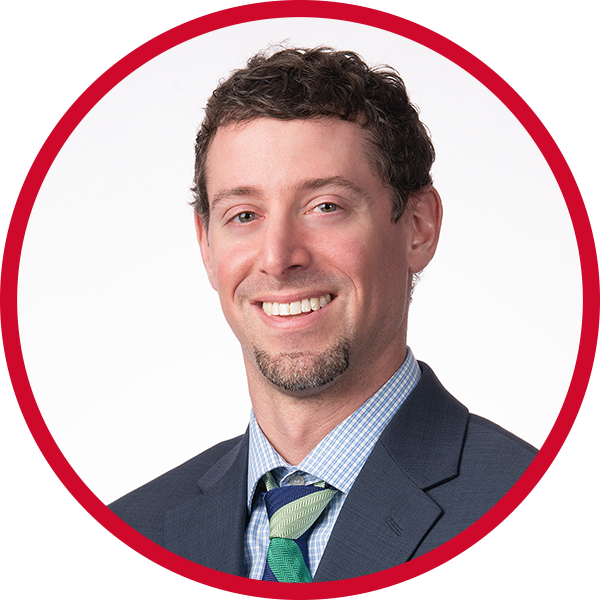 Professional headshot of a smiling man in a suit and tie, with a white background and red border.