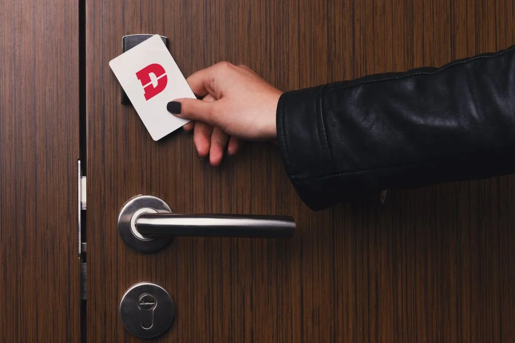 Person in a black leather jacket holding a key card over a door lock.