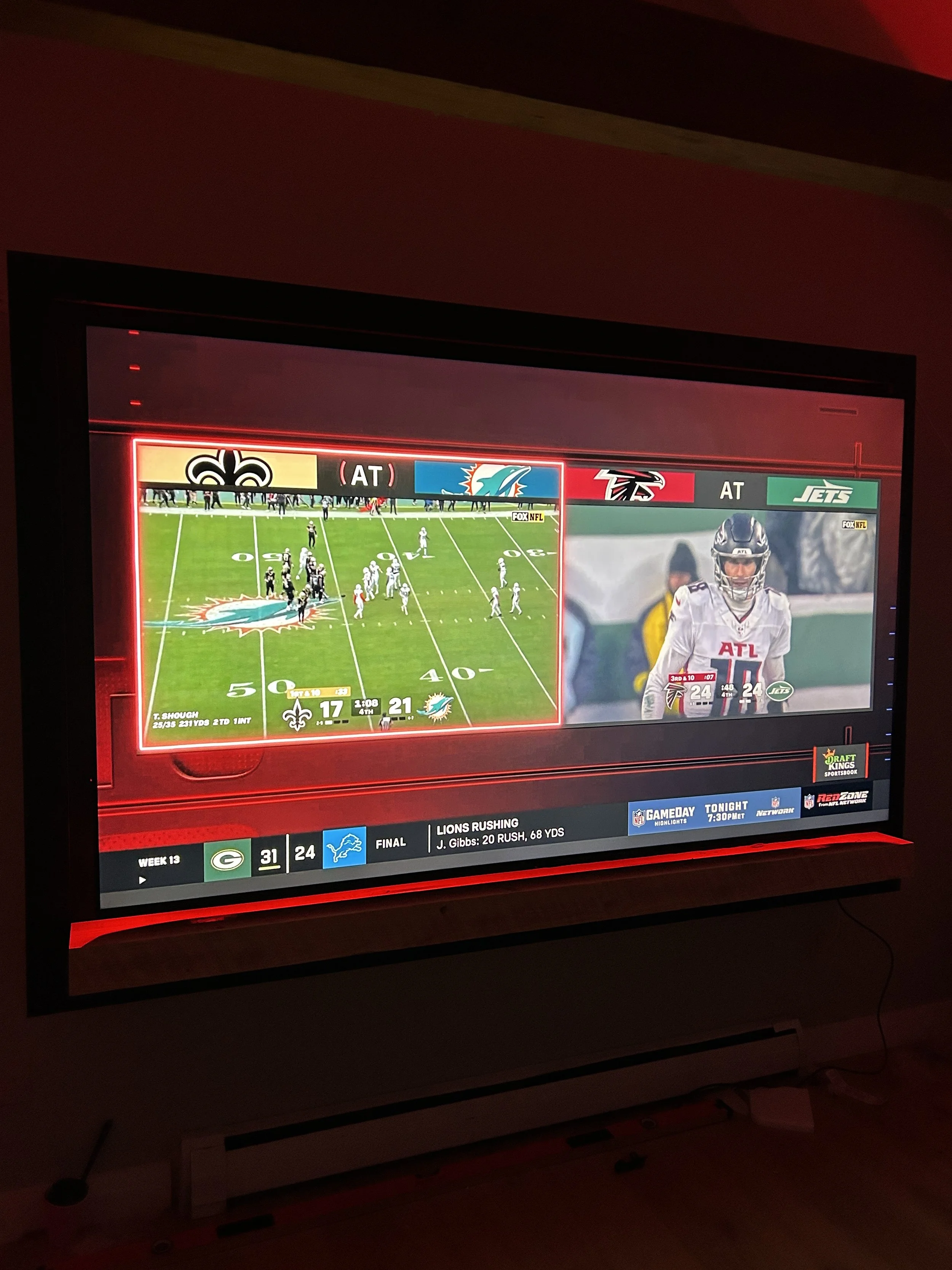 Television screen displaying a live American football game between the New Orleans Saints and the Miami Dolphins, with scores 17-21 in the fourth quarter, and a photo of a player from the Atlanta Falcons on the right side.