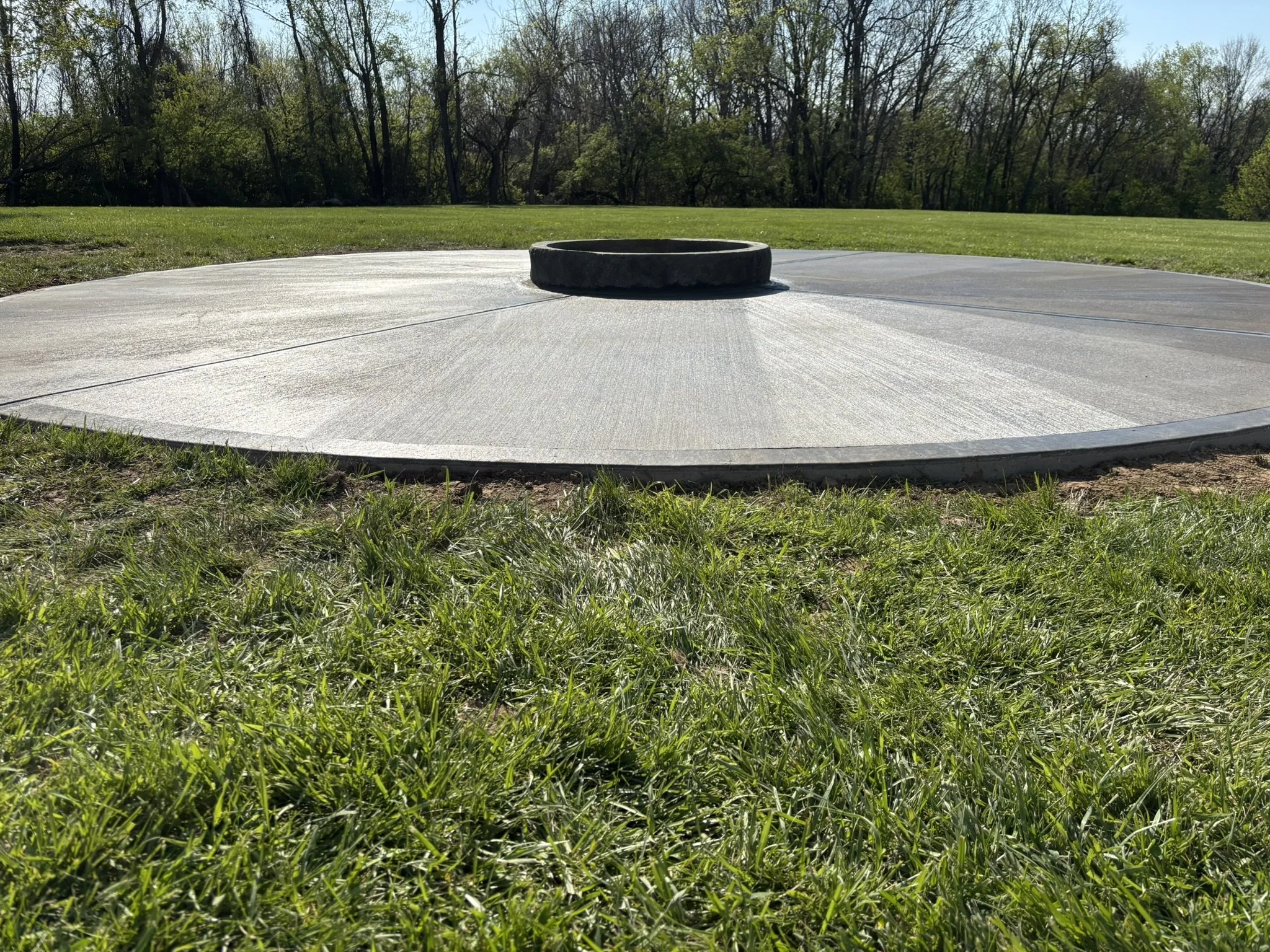 A disc golf basket in a grassy park with trees in the background.