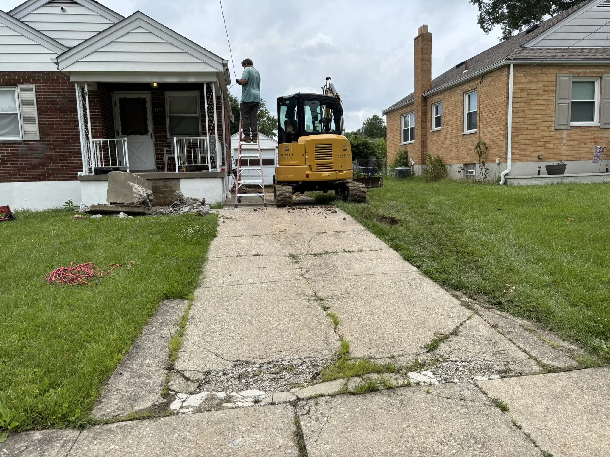 Man working on house roof with construction equipment in front yard