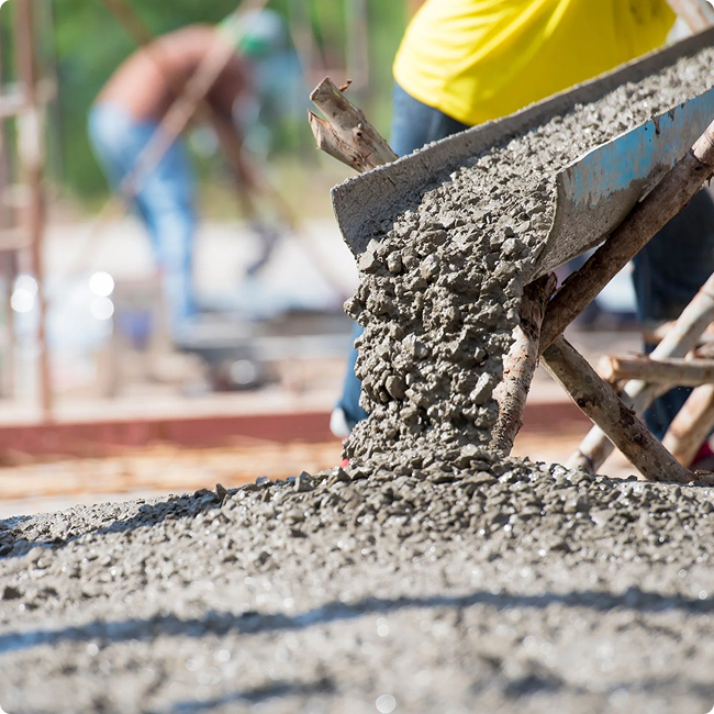 Concrete being poured from a wheelbarrow onto a construction site.