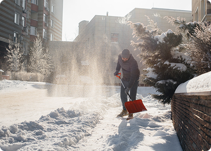 Person shoveling snow outside on a snowy day in an urban area.