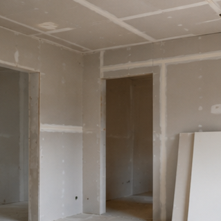 Interior of a room under construction with drywall installation in progress.