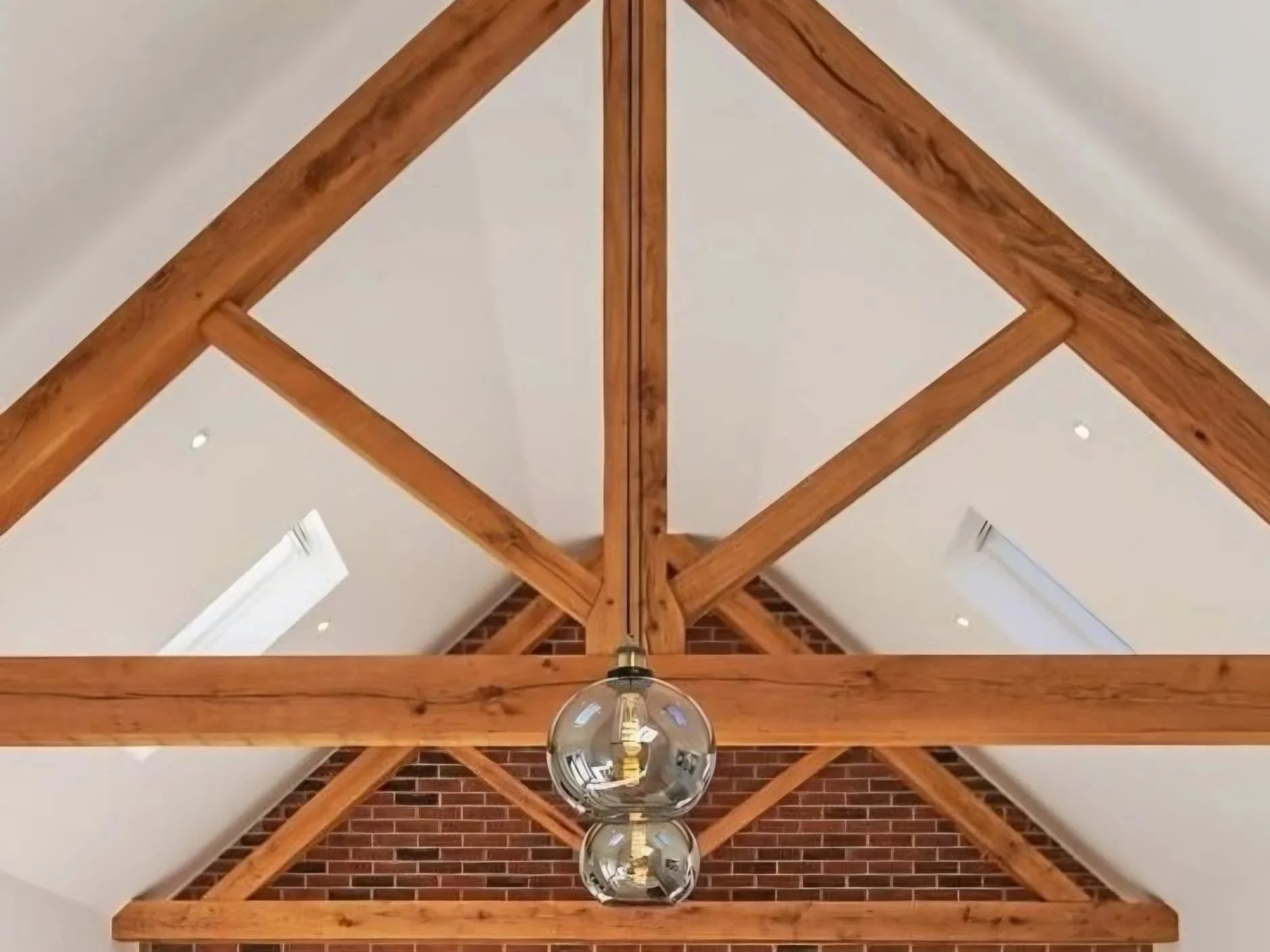 View of a ceiling with wooden beams, brick wall section, and hanging spherical glass light fixtures.