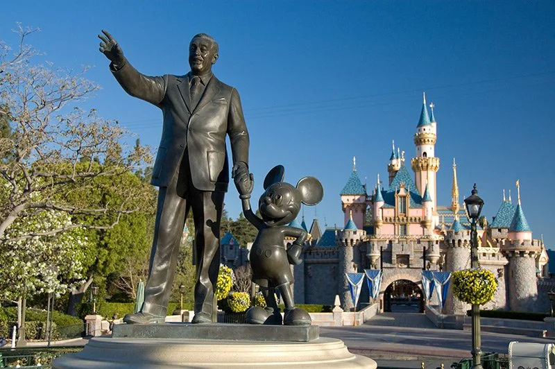 Statue of Walt Disney and Mickey Mouse in front of Sleeping Beauty Castle at Disneyland during daytime.