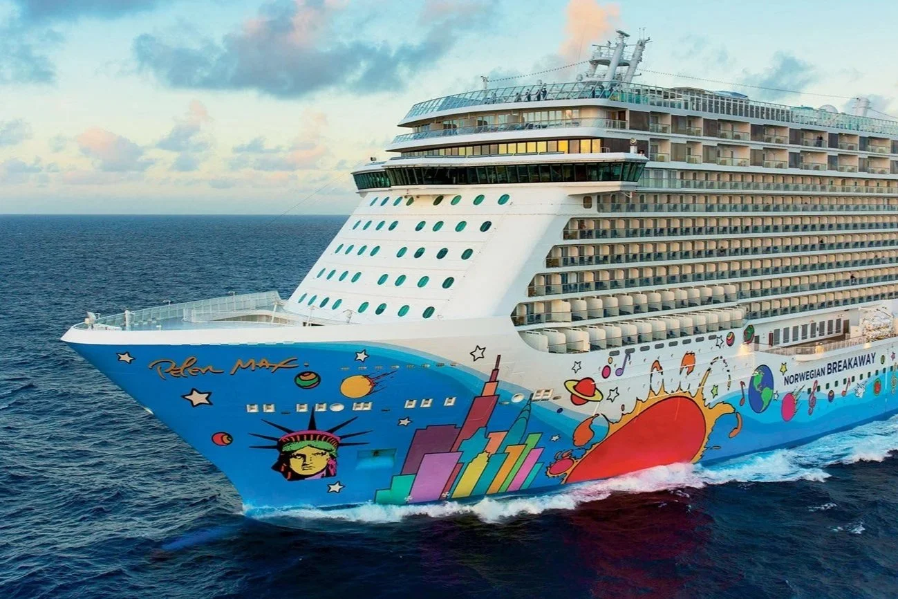 A colorful cruise ship sailing on the ocean with vibrant space-themed artwork on the hull, including planets, stars, and a rocket.