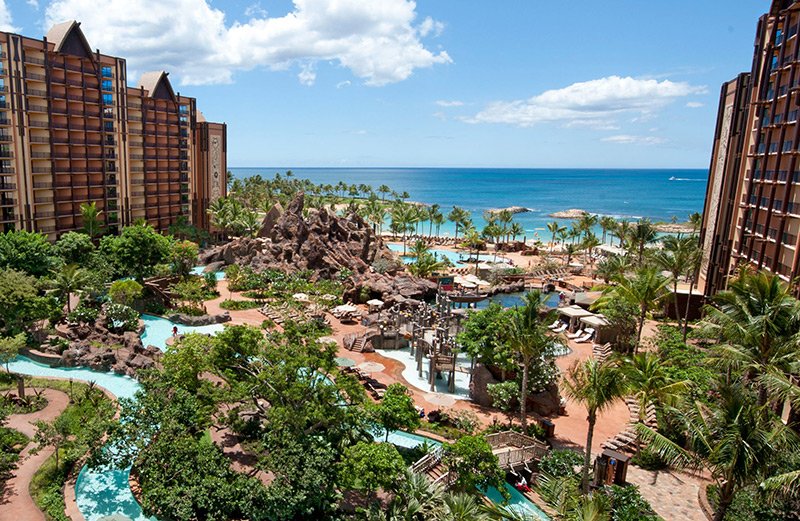 Beachside resort with pools, palm trees, and buildings overlooking the ocean.