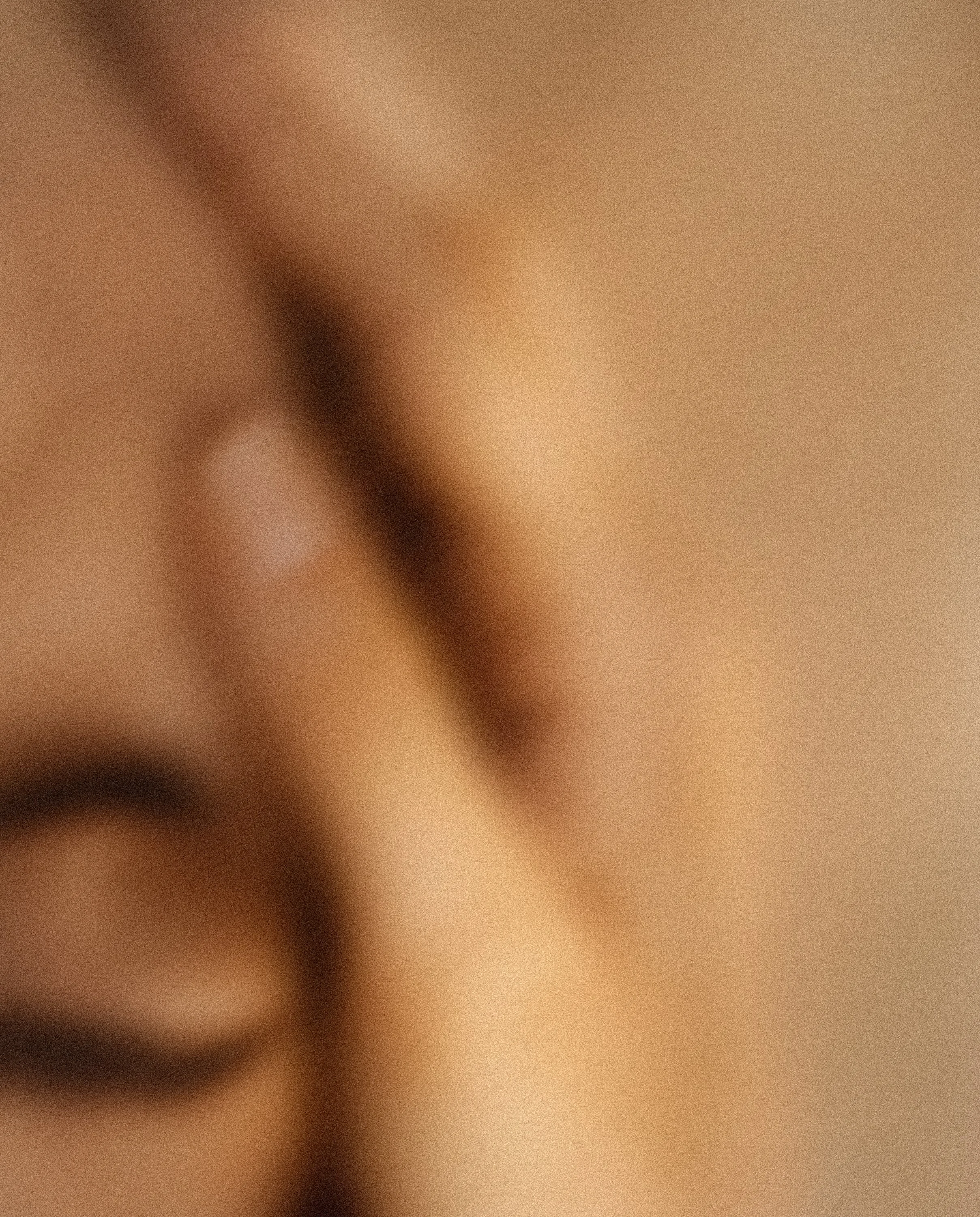 An extreme close-up of a human face showing the eye and eyebrow, with a warm complexion and soft lighting.