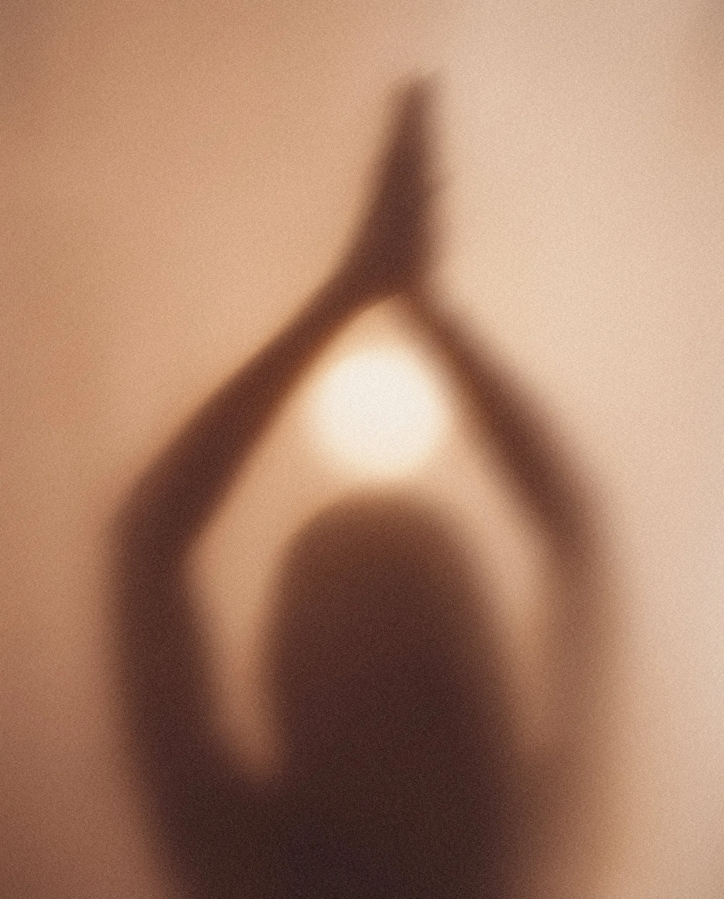 A blurred image showing a hand holding a pen or similar object, with a piece of paper or surface underneath, in warm tones.