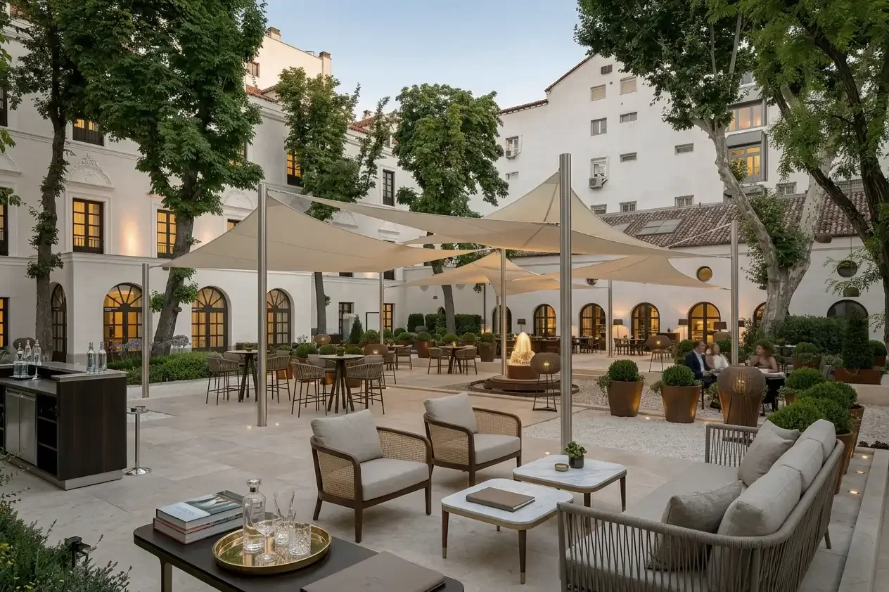 restaurante de hotel de lujo con mesas altas y sillones, la zona de la terraza esta cubierta con velas de sombra color crema que le dan calidez y aportan sombra y un ambiente elegante