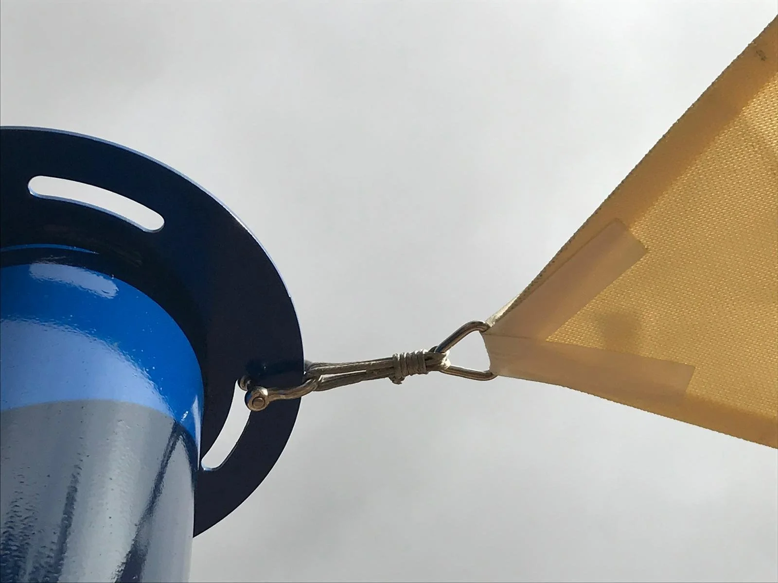 Detalle de unión entre poste azul y vela de sombra a medida color crema