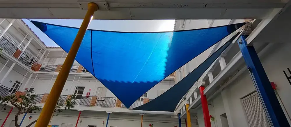 Patio de un colegio en Malaga con velas de sombra azules