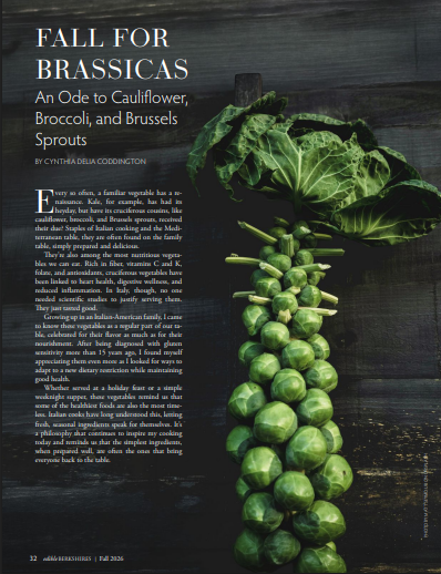 A bunch of Brussels sprouts attached to a stalk, set against a dark wooden background.