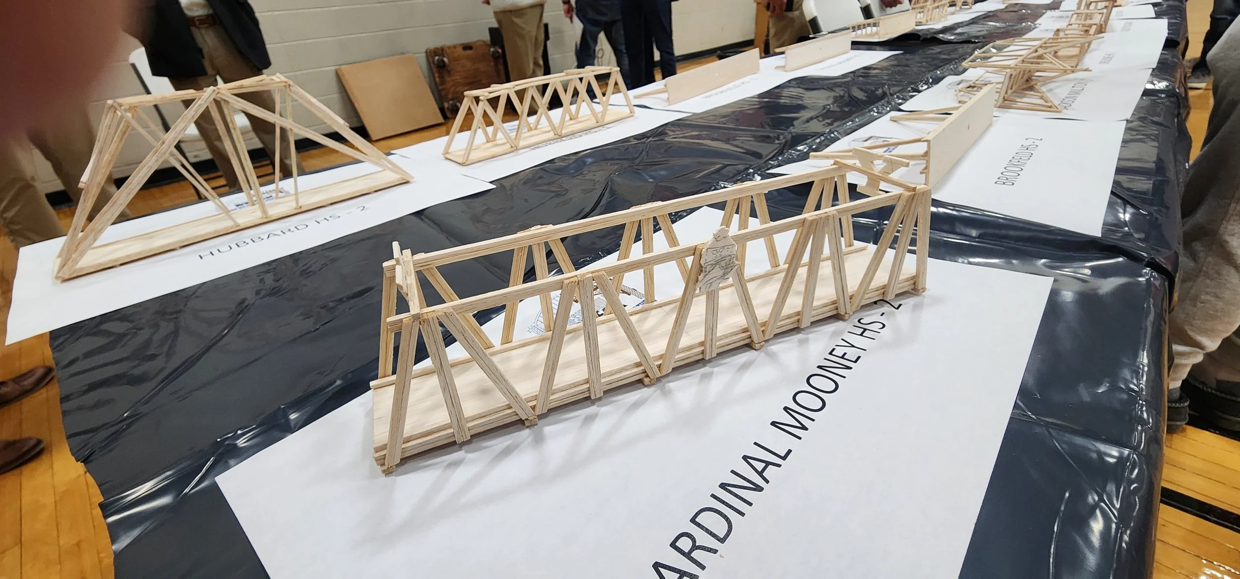 Wooden truss models arranged on tables for a bridge-building competition.