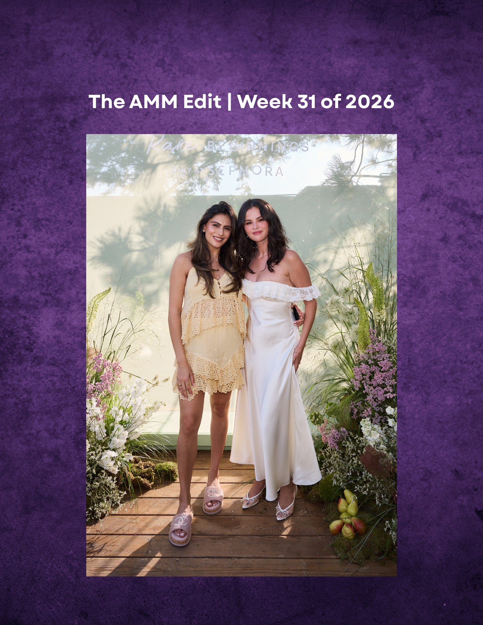 Two women, one wearing a yellow crochet dress and the other in a white dress, standing on a wooden platform surrounded by flowers and greenery, smiling at the camera.