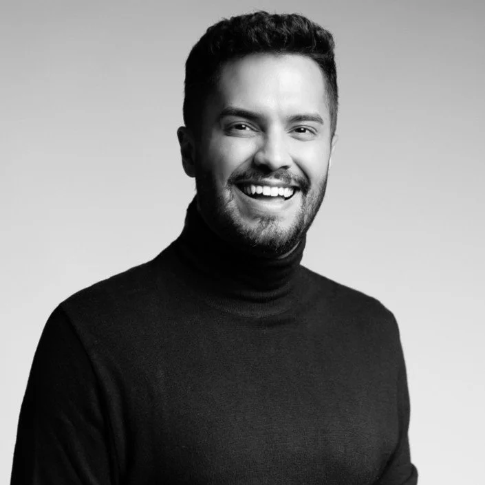 Black and white portrait of a smiling man in a black turtleneck.