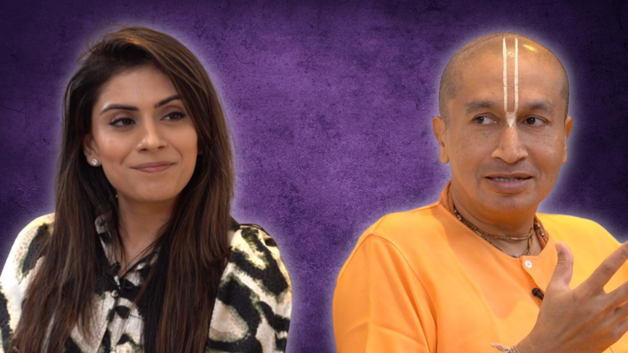 A woman with long brown hair and a man with a shaved head and cultural markings on his forehead, dressed in orange, against a purple background.
