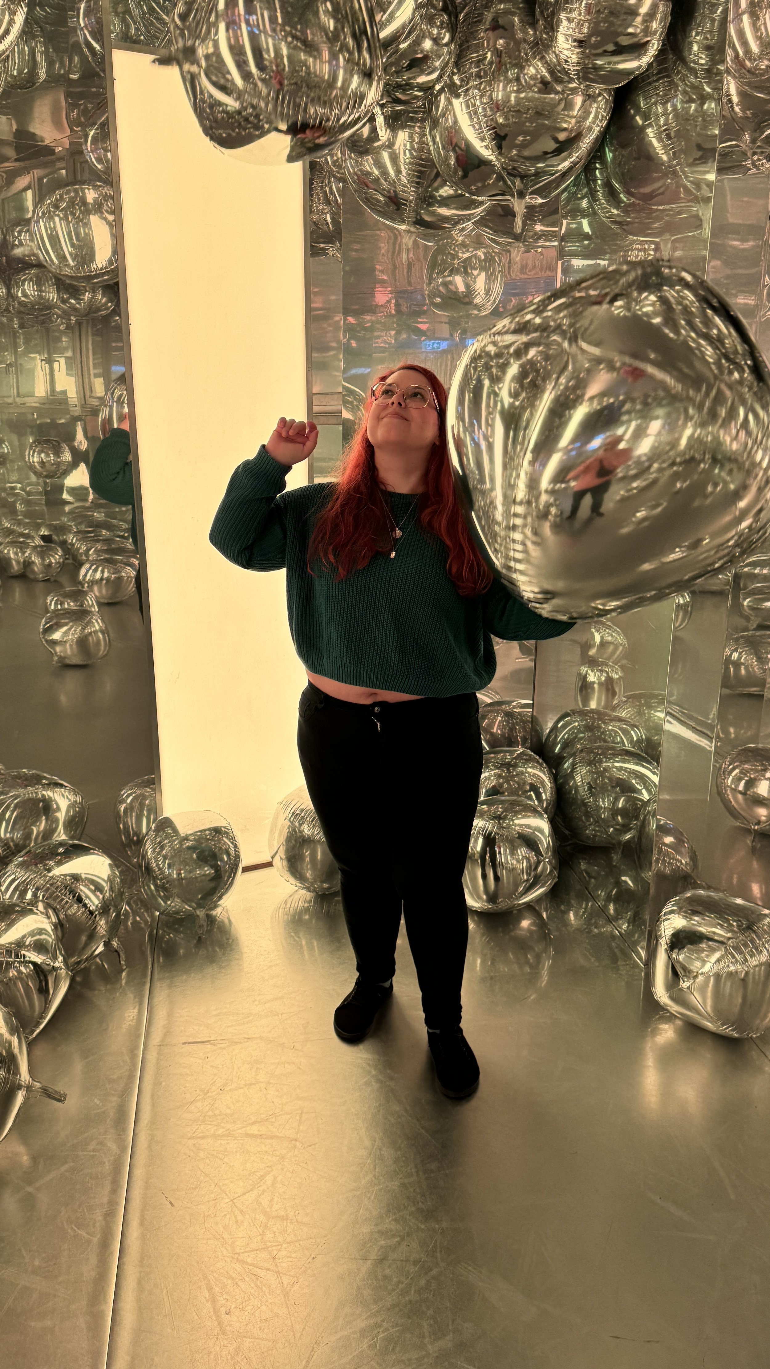 Nadine Spagnolo staunend in einer Spiegelinstallation mit Silberballons – kreative Energie hinter ORIGIN & ECHO